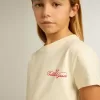 Tricou din bumbac pentru fete, de culoare albă uzată, cu broderie roșie pe piept Tricou din bumbac pentru fete, de culoare albă uzată, cu broderie roșie pe piept
